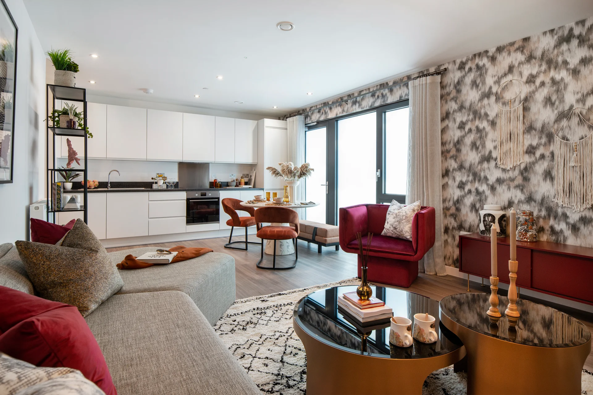 Modern living room featuring a stylish sofa, red accent chairs, and a decorative coffee table with a geometric rug.