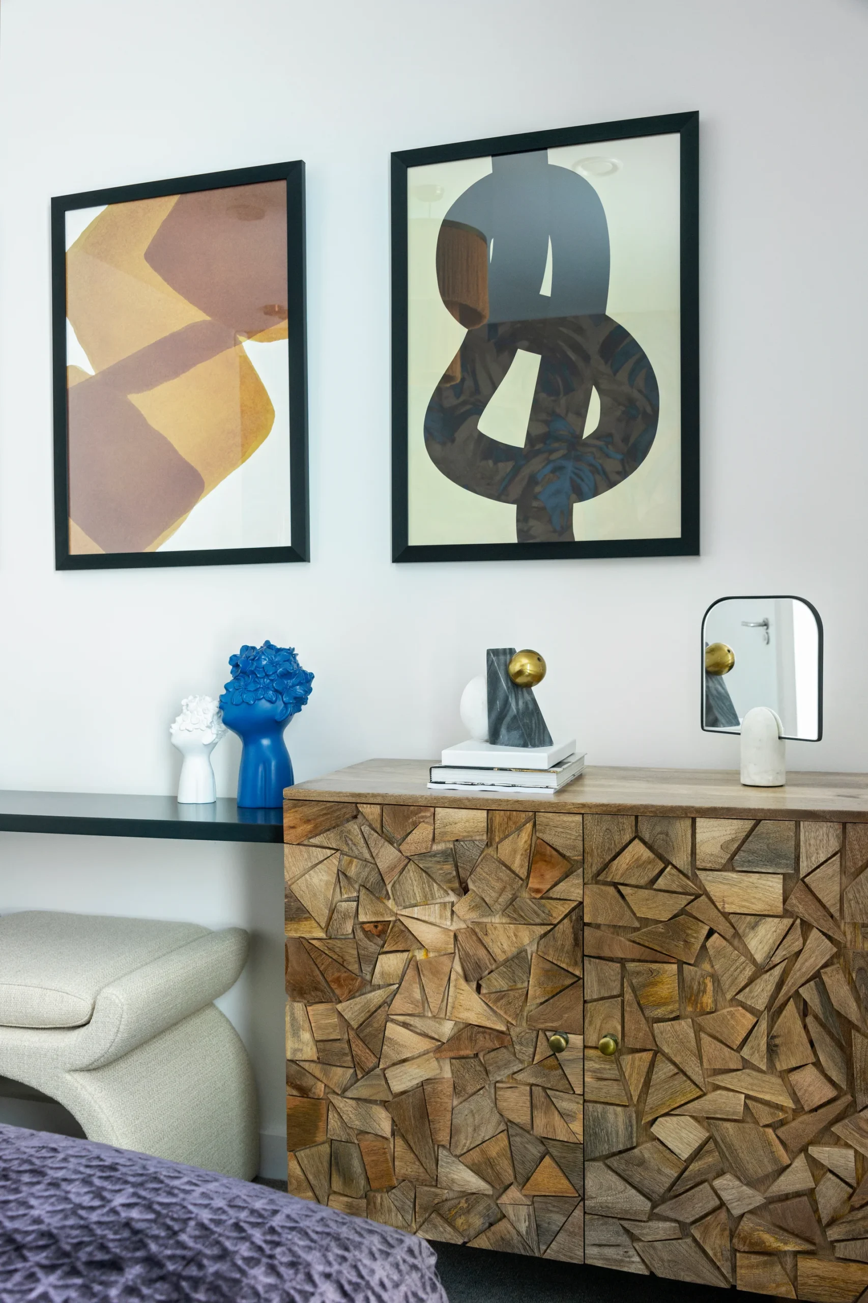 Modern interior featuring abstract wall art, a textured wooden cabinet, and decorative objects on a sleek table.