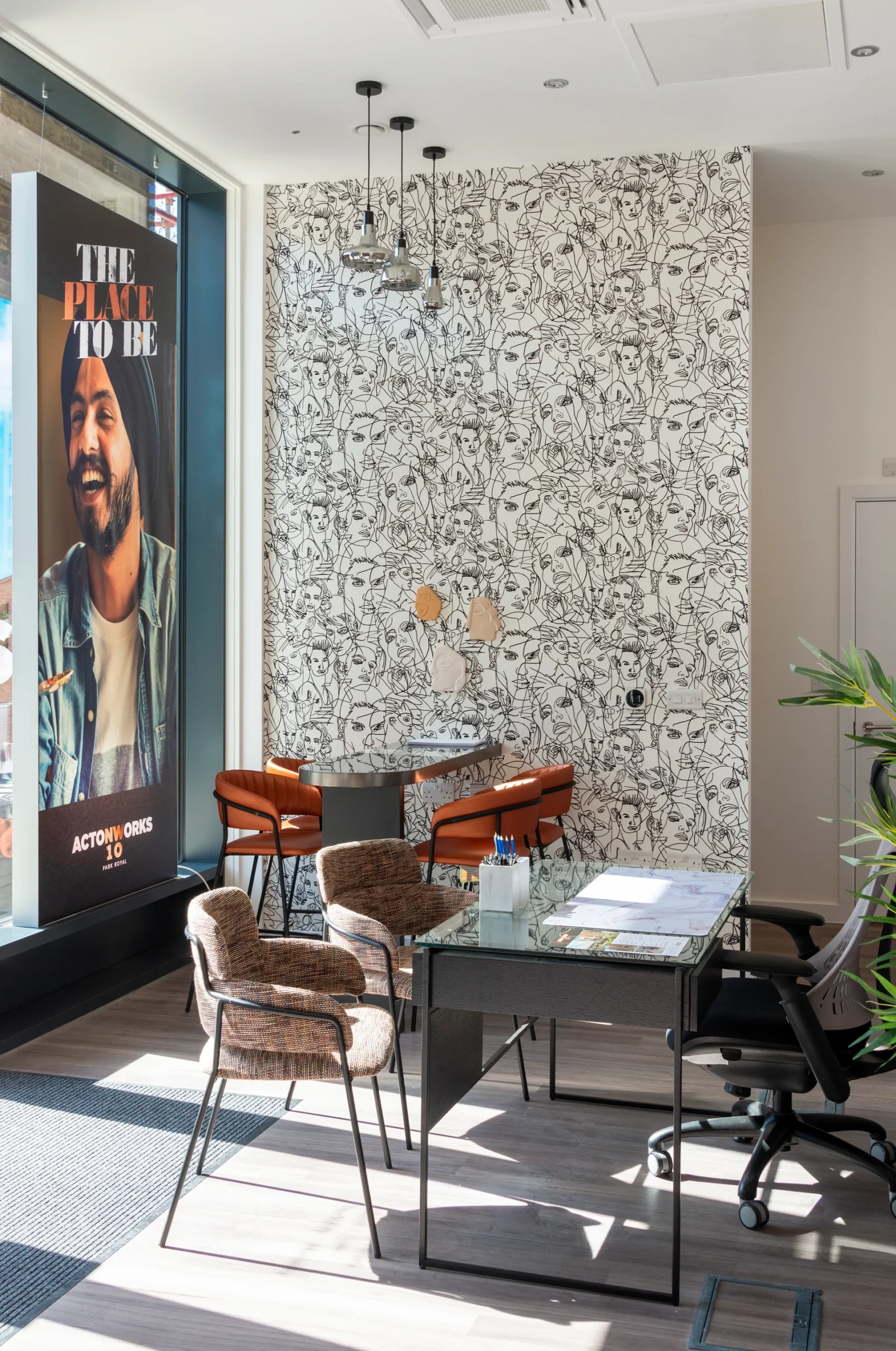 Bright and modern workspace featuring a patterned wall, seating area, and a large window with a motivational poster.