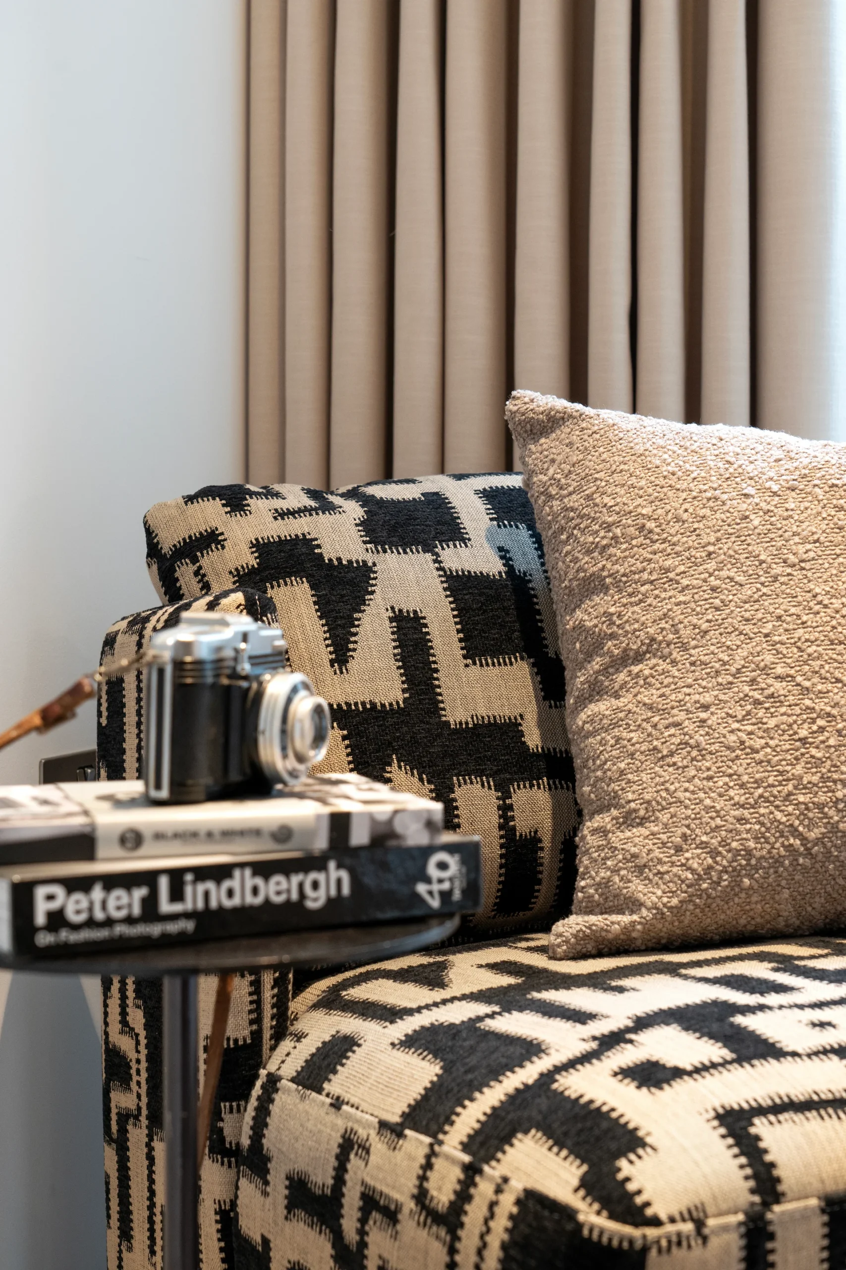 A patterned couch with a decorative pillow, a camera, and a book titled "Peter Lindbergh" on a side table.