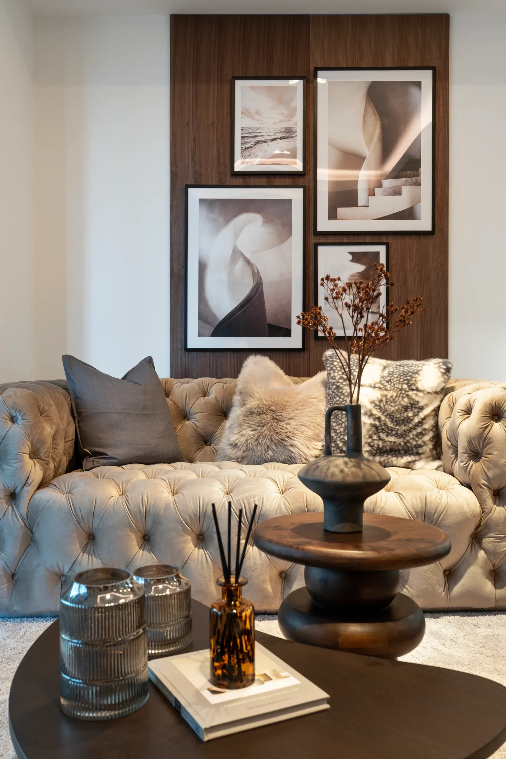 Cozy living room with a tufted sofa, decorative pillows, artwork on the wall, and a stylish coffee table.