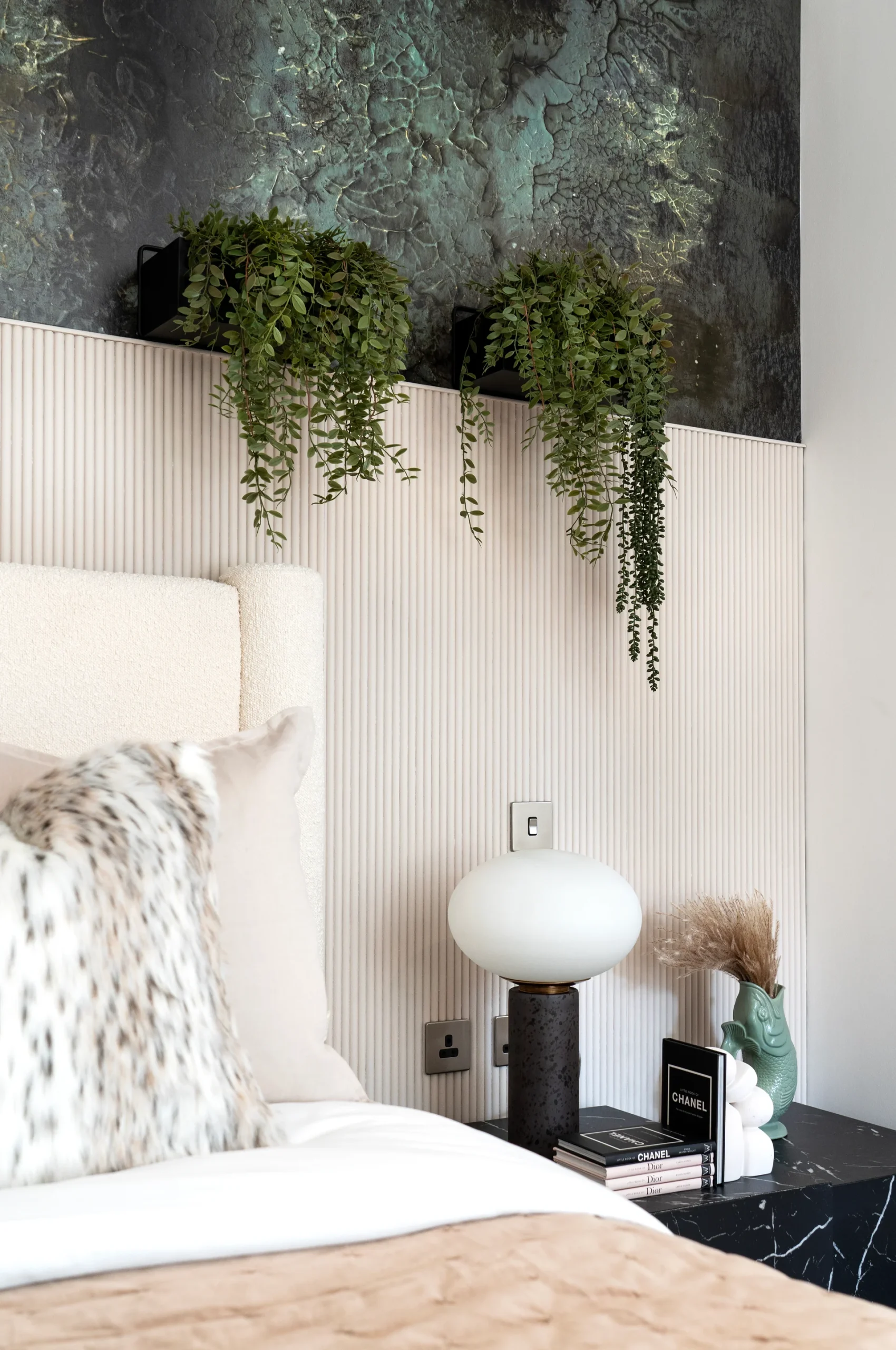 Modern bedroom interior featuring potted ferns, a cozy bed with pillows, and a stylish lamp on a bedside table.
