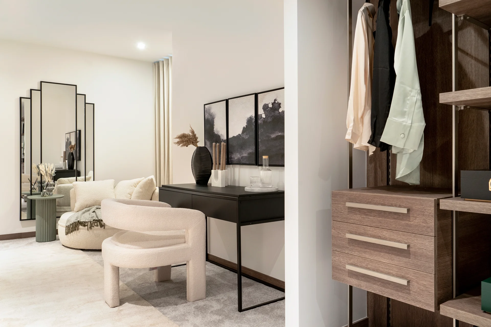 Modern living space featuring a stylish chair, a console table with decor, and a wardrobe with hanging clothes.