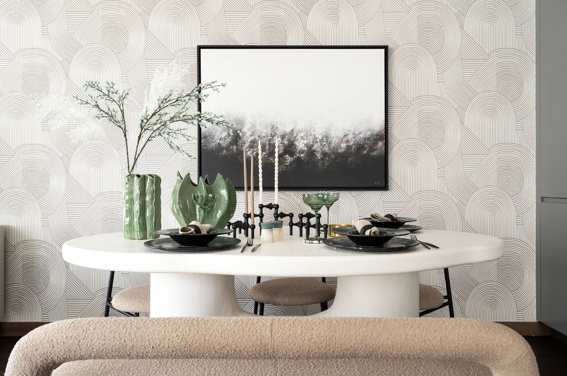 Modern dining table set with greenery, candles, and a black and white wall art piece in a stylish interior.