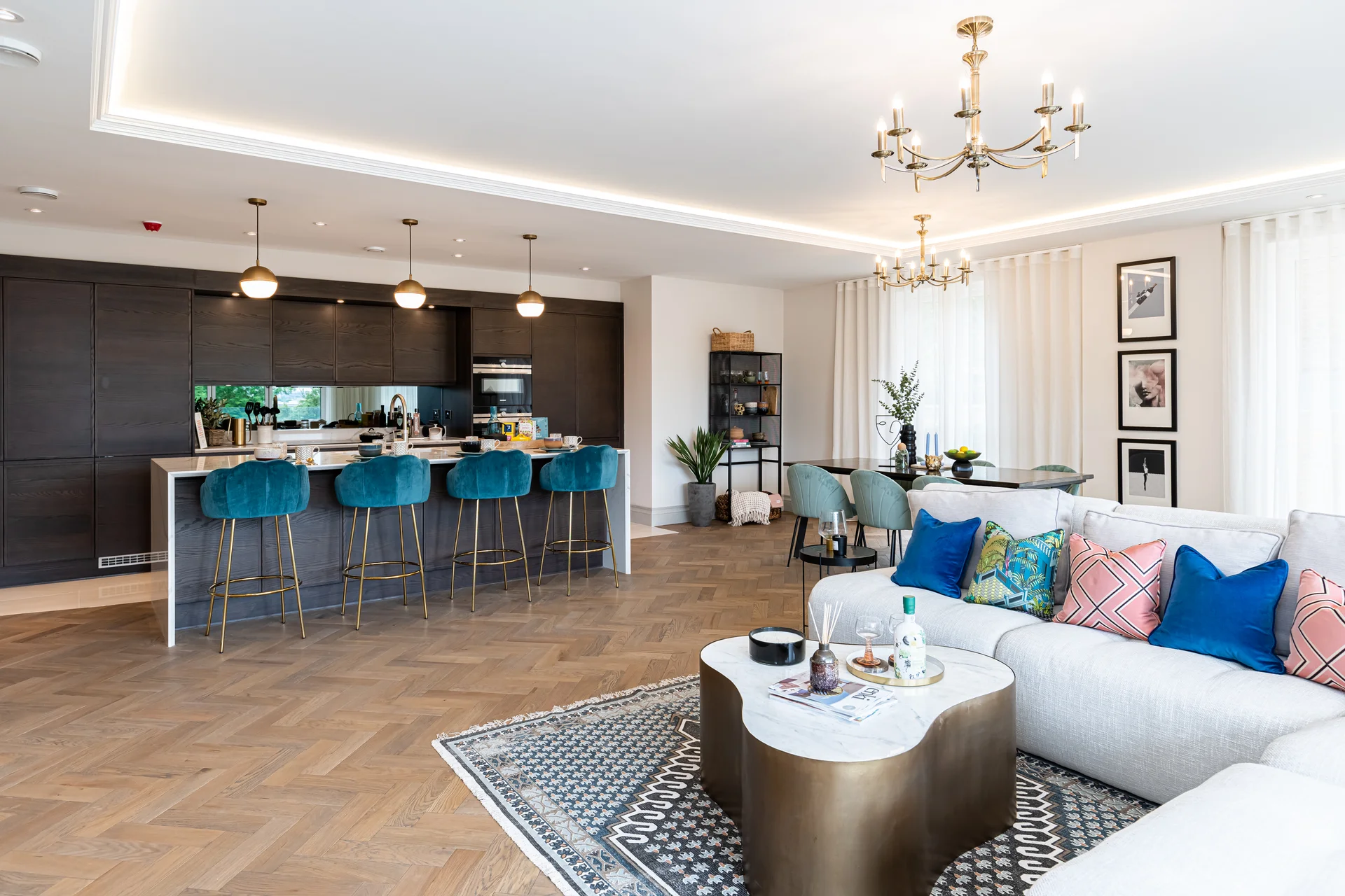 Modern living room with a sleek sofa, decorative pillows, and a bar area with blue stools in a bright, stylish interior.