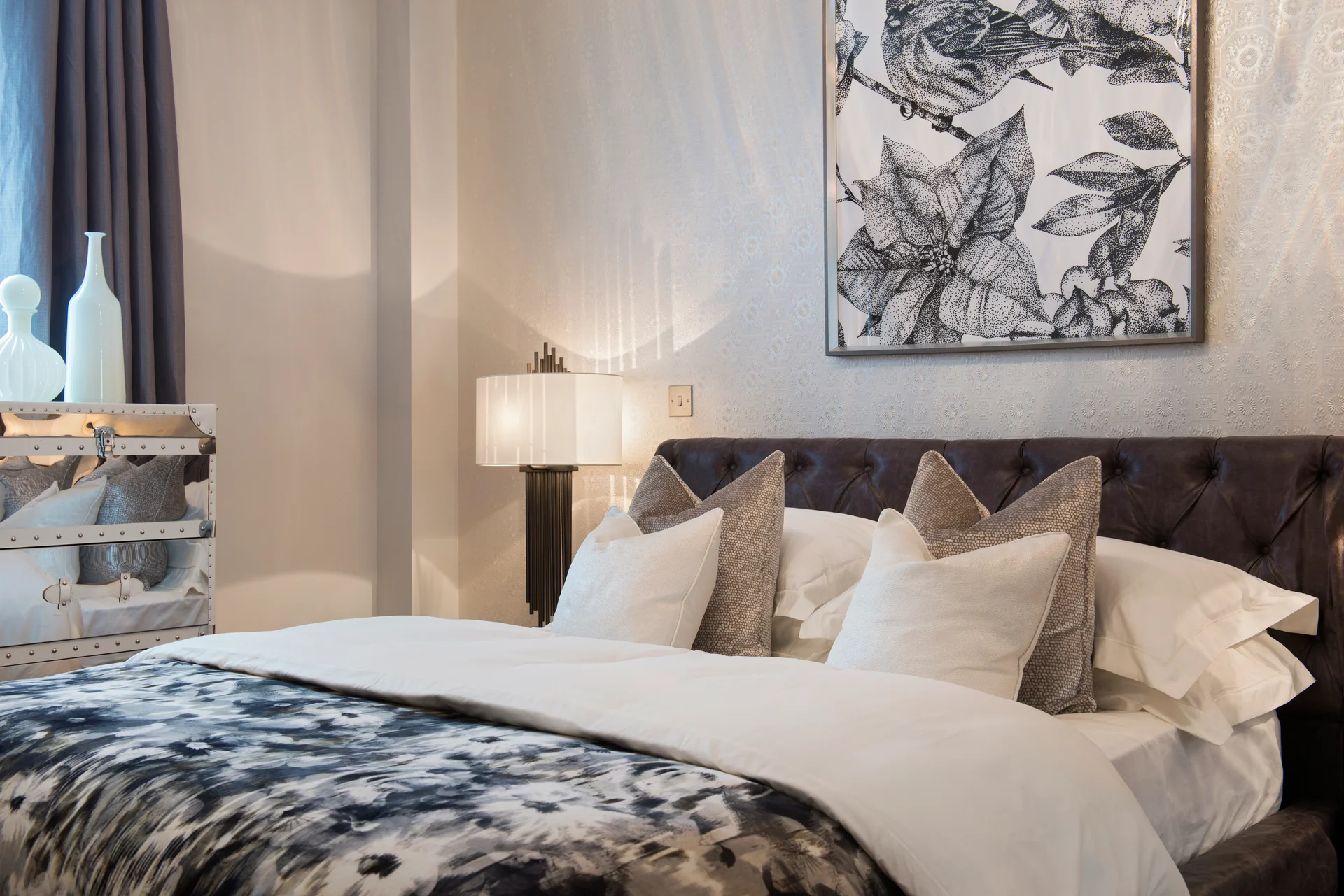 Luxurious bedroom featuring a tufted headboard, decorative pillows, and an art piece above the bed.
