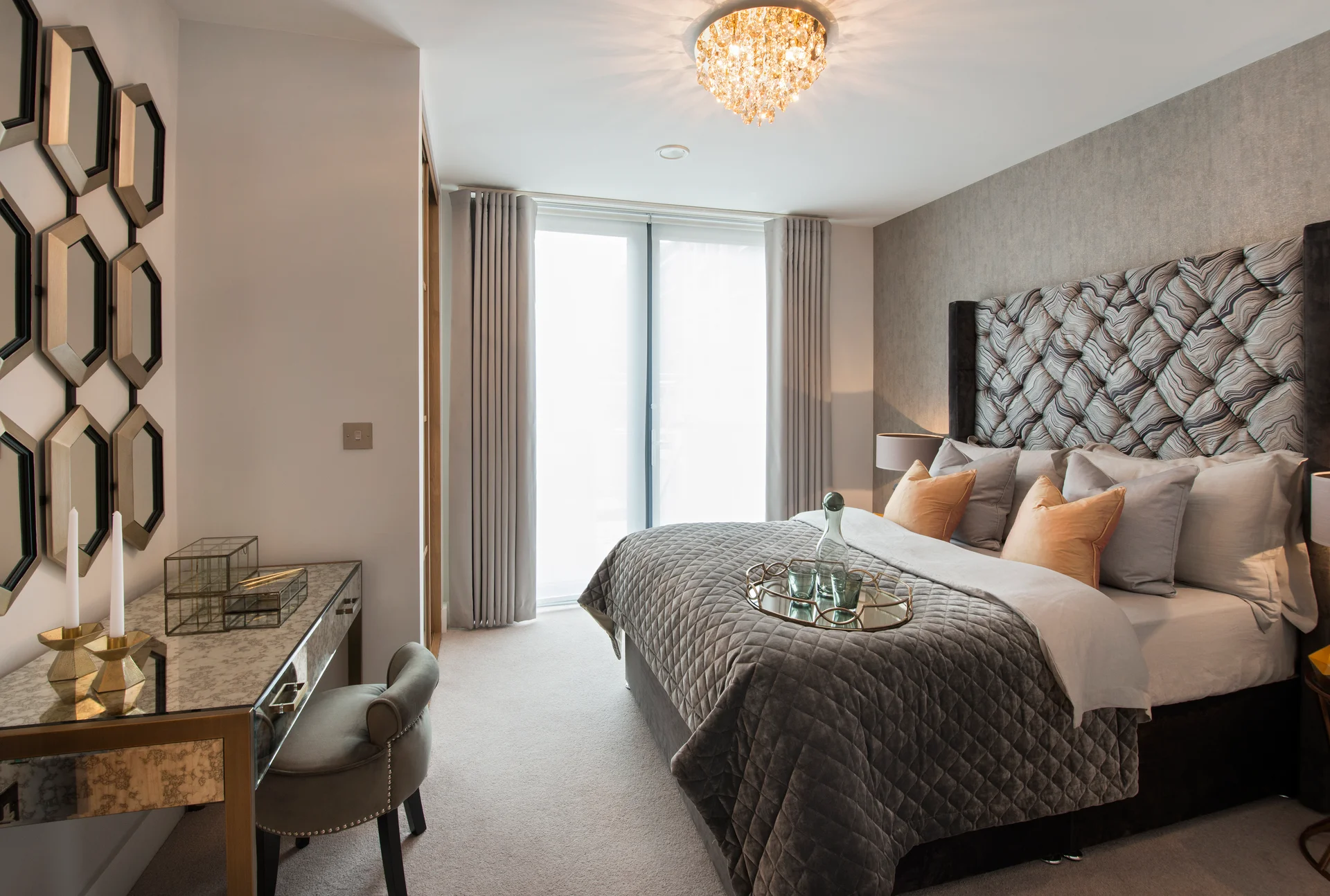 Modern bedroom with a large bed, stylish decor, a chandelier, and a mirror accent wall.