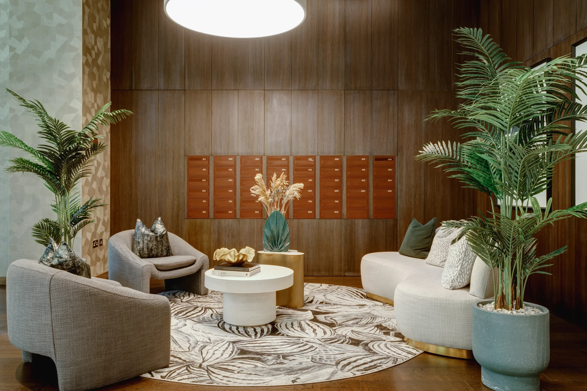 Modern reception area featuring cozy seating, decorative plants, and a round coffee table on a patterned rug.
