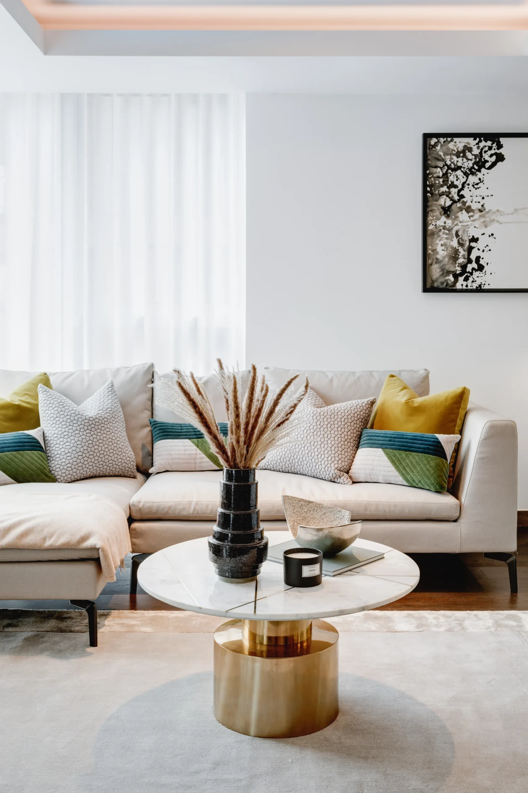 Cozy living room featuring a light sofa with colorful pillows, a marble coffee table, and a decorative vase.