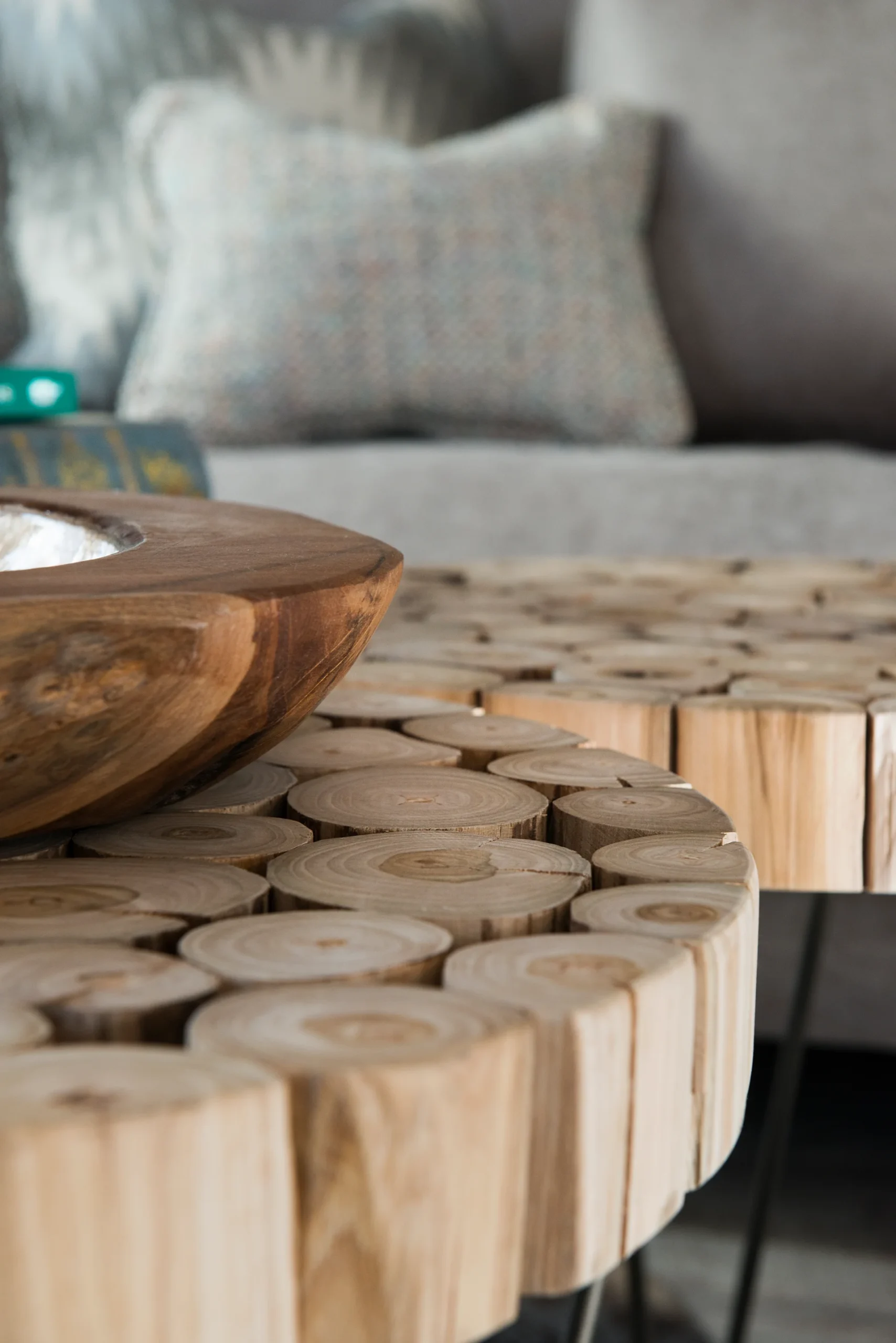 Wooden coffee tables with circular cut logs and a large wooden bowl, set in a cozy living room.