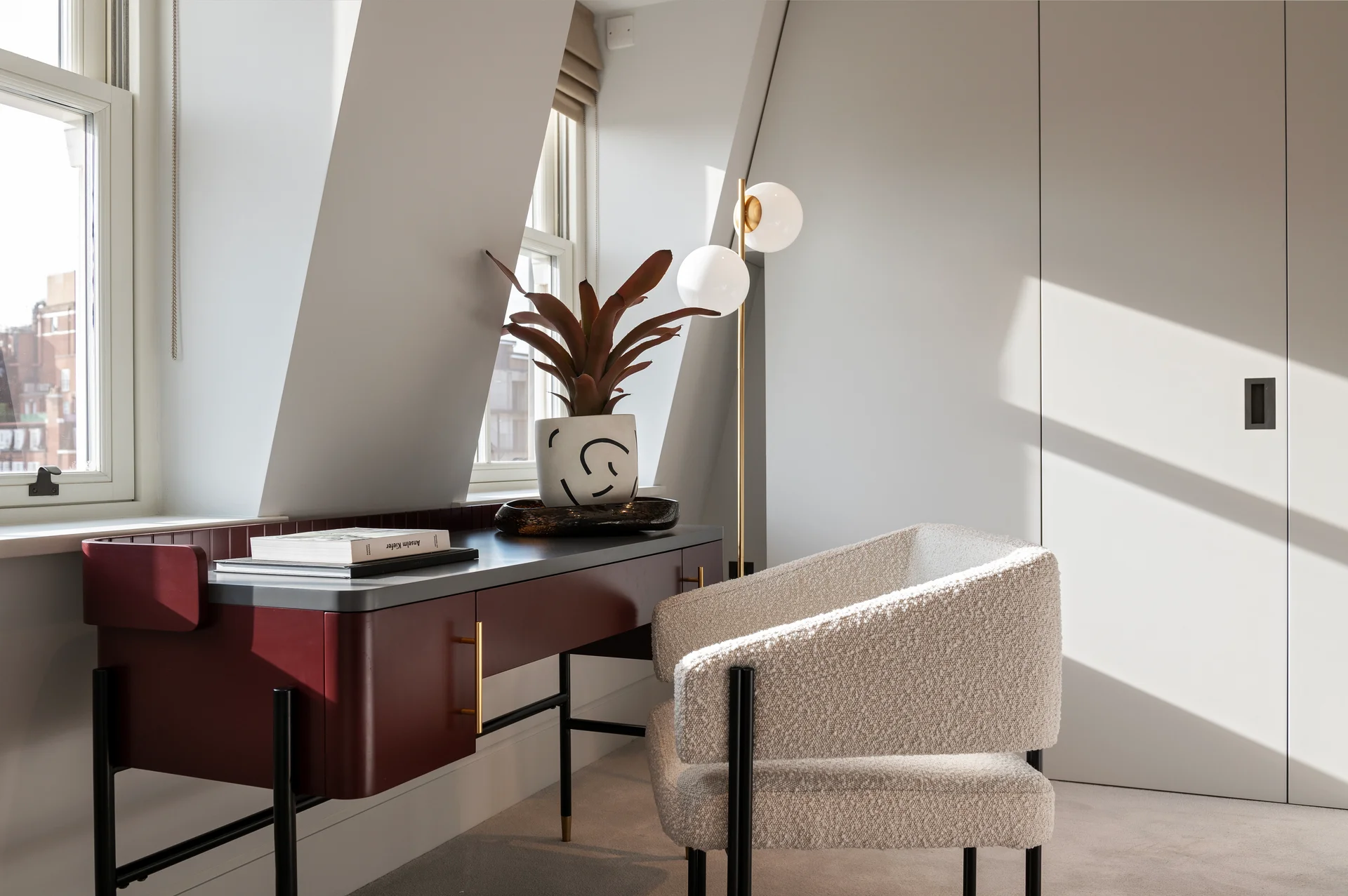 Cozy workspace featuring a modern desk with decorative plants and a stylish chair, illuminated by natural light.