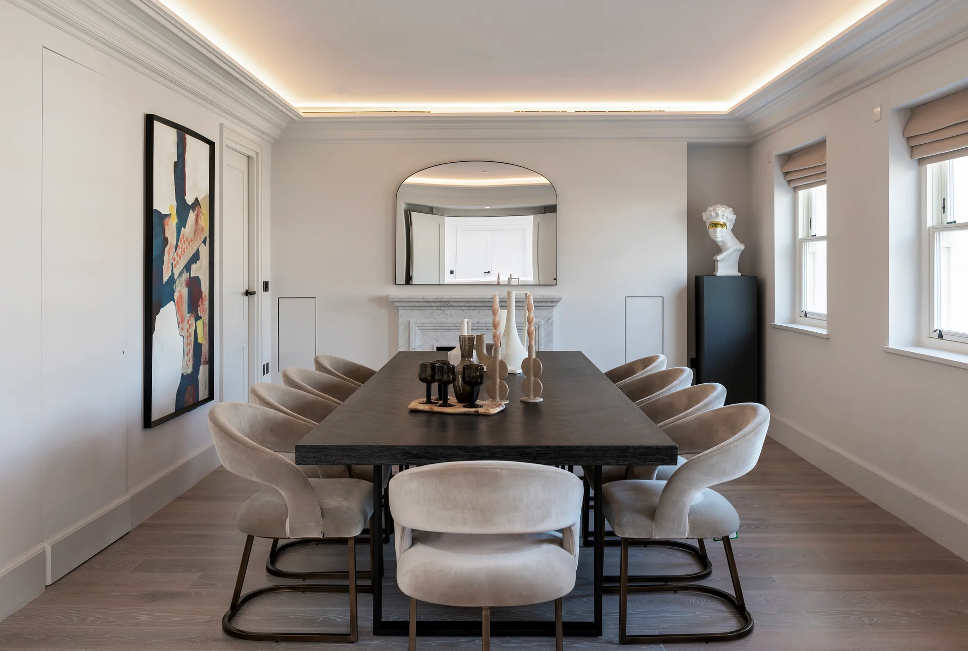Modern dining room featuring a long table, stylish chairs, and decorative wall art. Soft lighting enhances the ambiance.