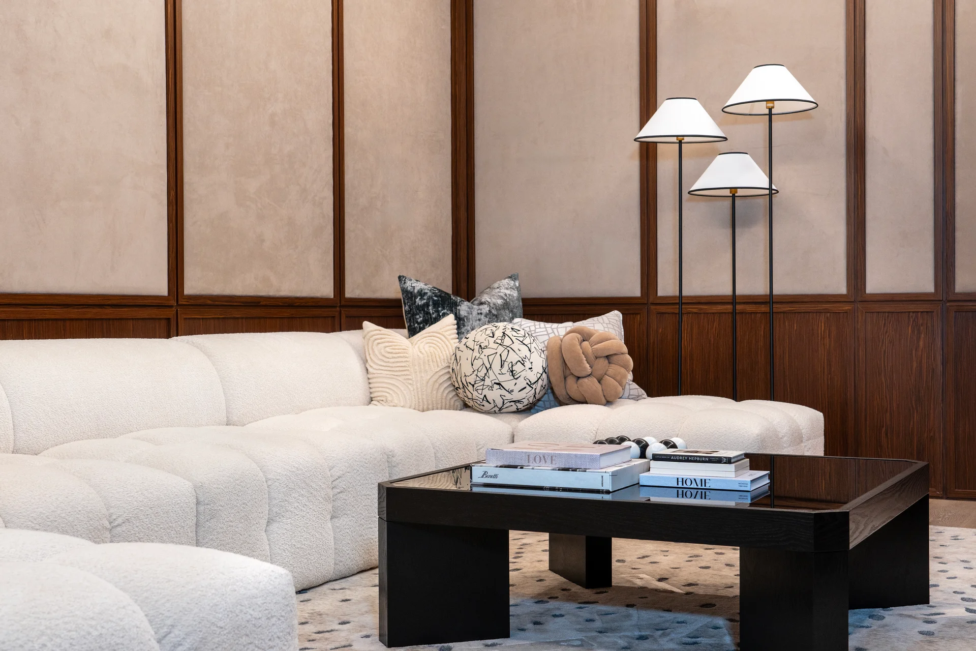 Cozy living room featuring a white sectional sofa, plush pillows, and a dark coffee table with magazines, complemented by