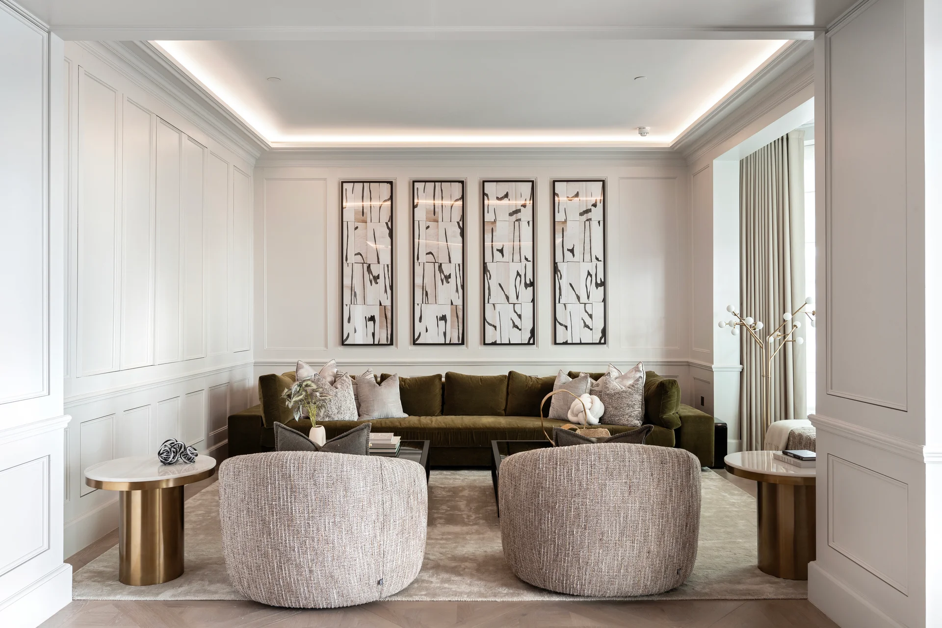 Modern living room featuring a green sofa, two round armchairs, and framed art on the wall. Bright, neutral color scheme.