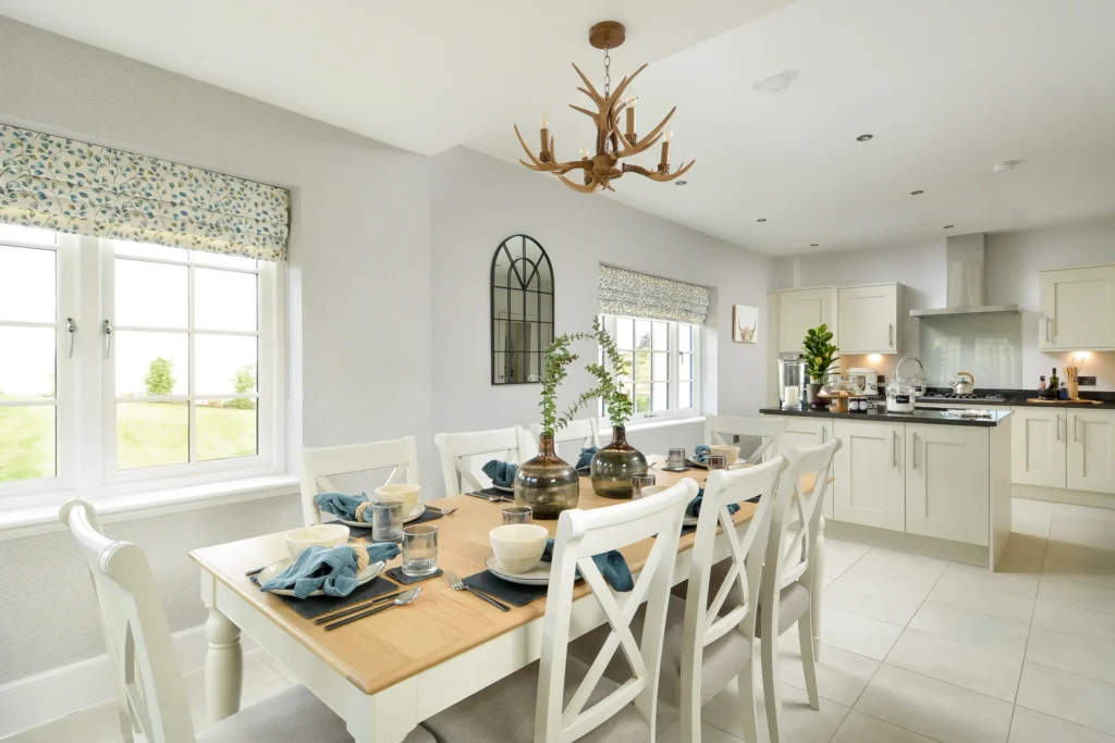 Bright kitchen with a dining table set for six, featuring blue place settings and a modern design with white cabinetry.