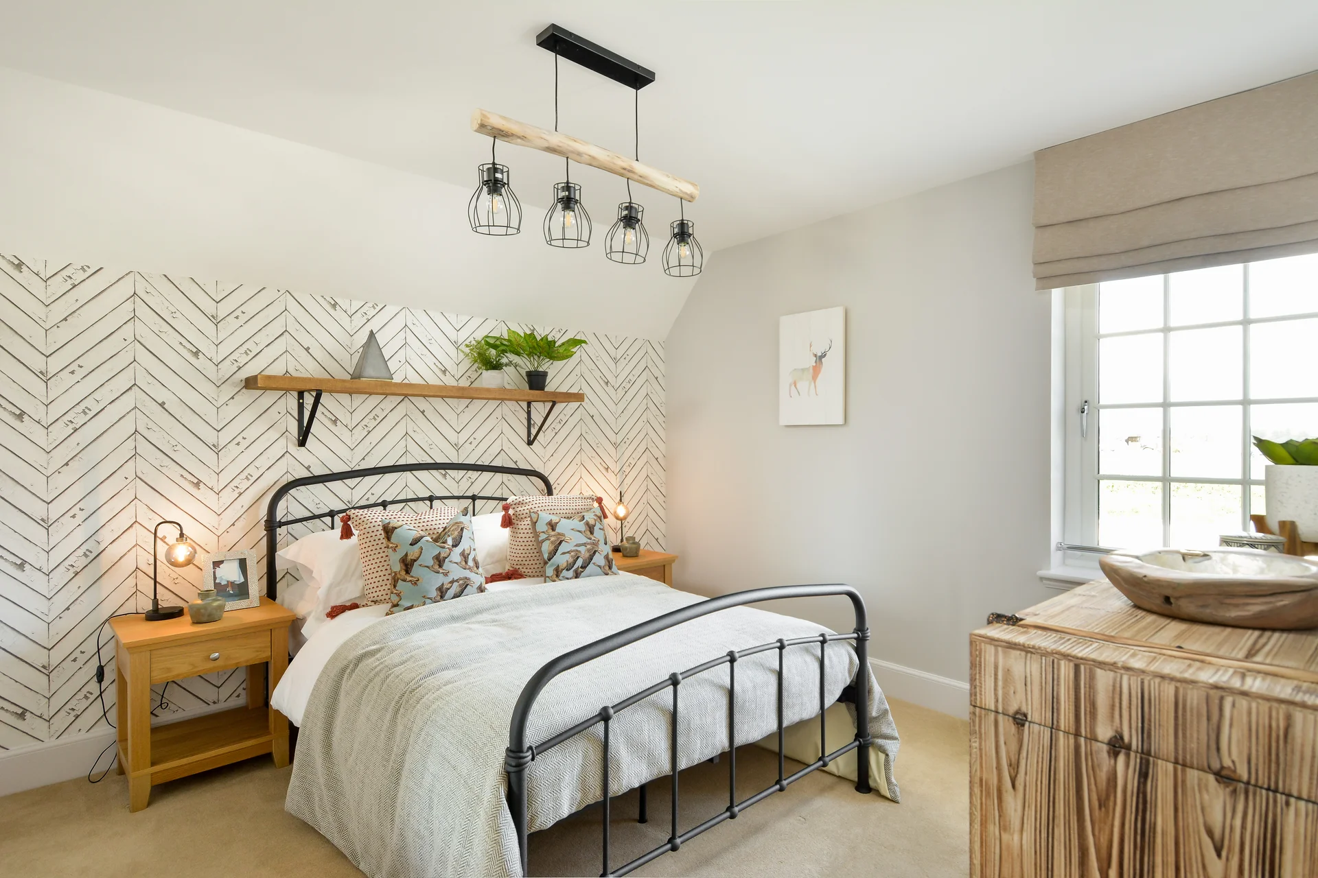Bright bedroom with a metal bed frame, herringbone accent wall, pendant lights, and natural décor elements.