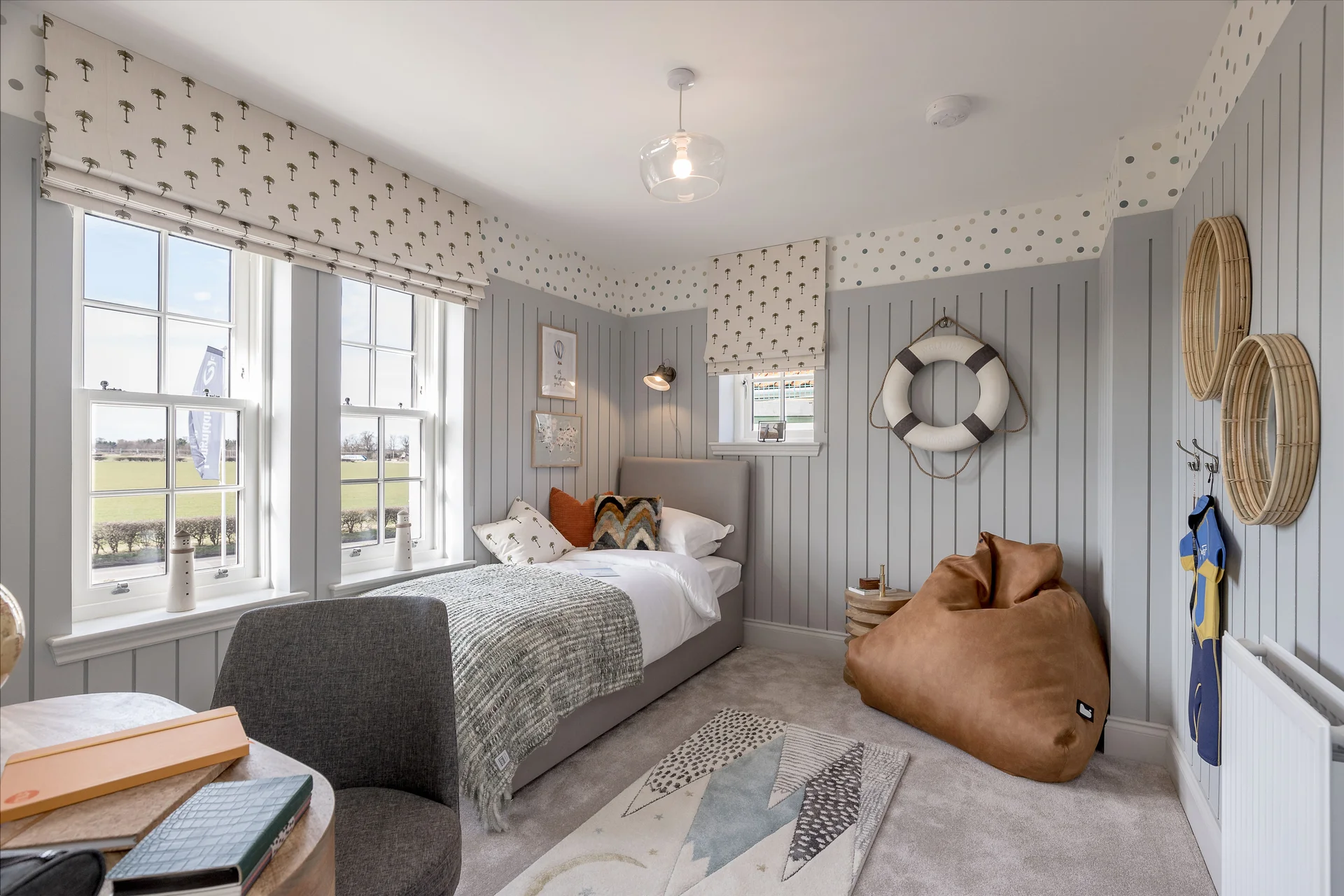 Cozy bedroom with gray walls, a single bed, bean bag chair, and large windows letting in natural light.