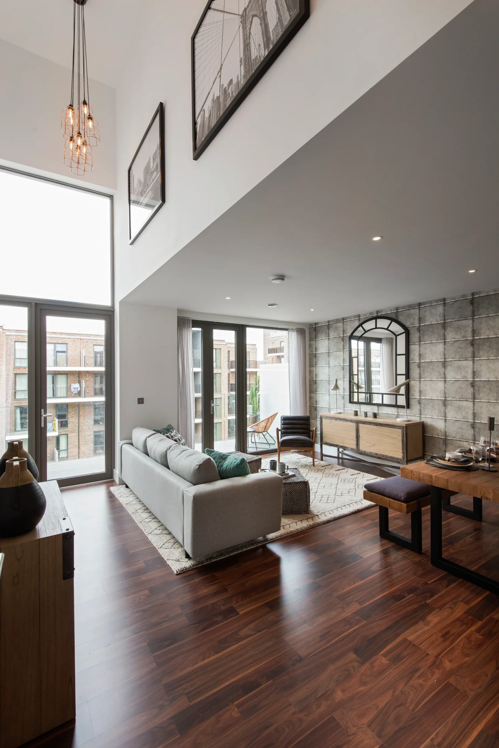 Modern living room with a large window, stylish furniture, and decorative wall art. Warm wooden flooring enhances the space.