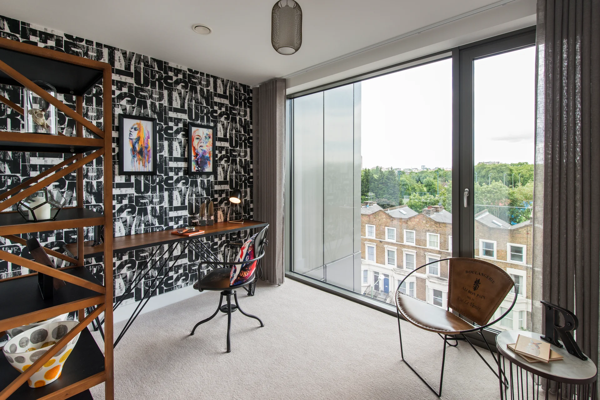 Stylish interior featuring a work desk, shelving, and large windows with views of greenery and buildings outside.
