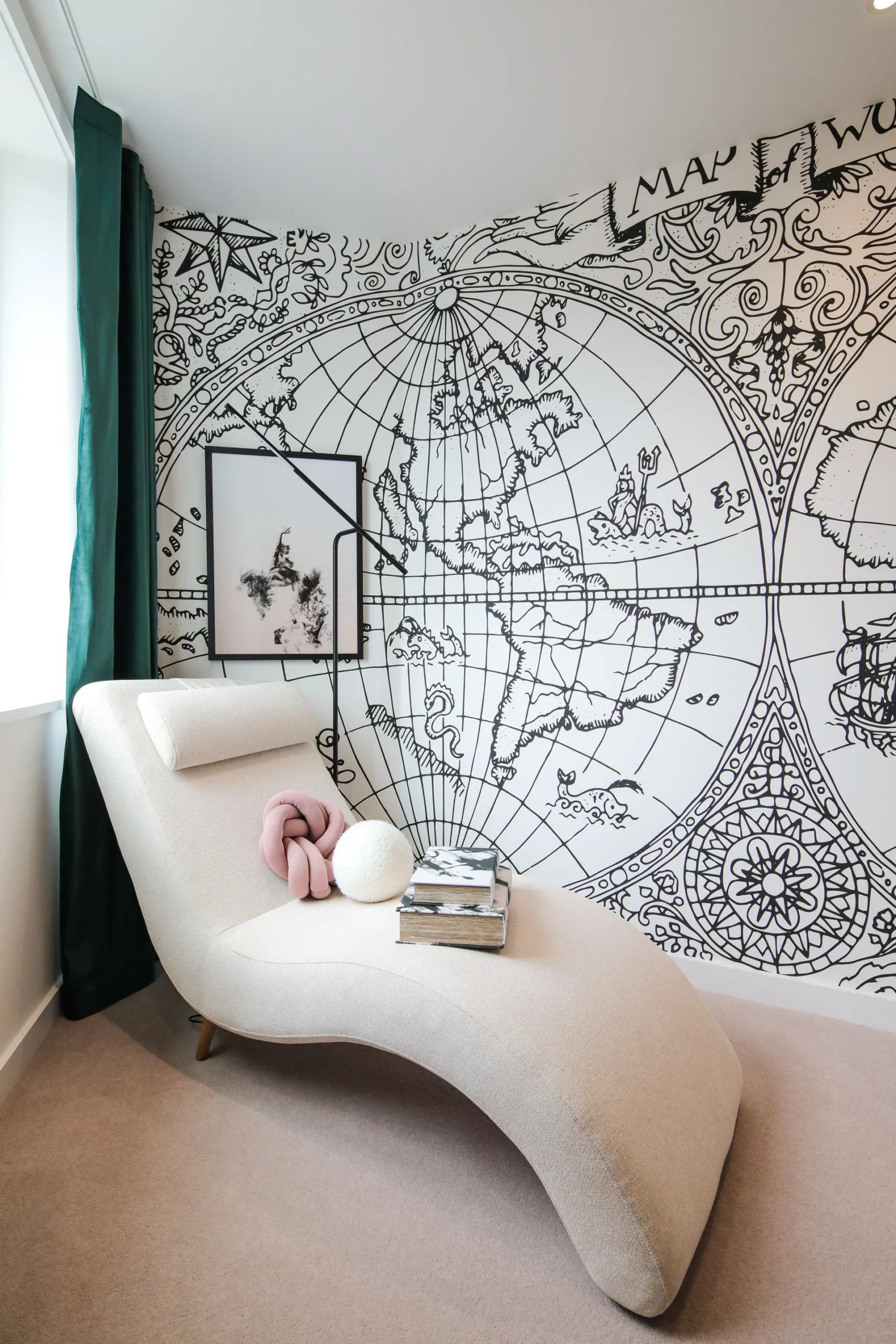 Contemporary lounge area featuring a curved chaise lounge, decorative globe mural, and a stack of books.