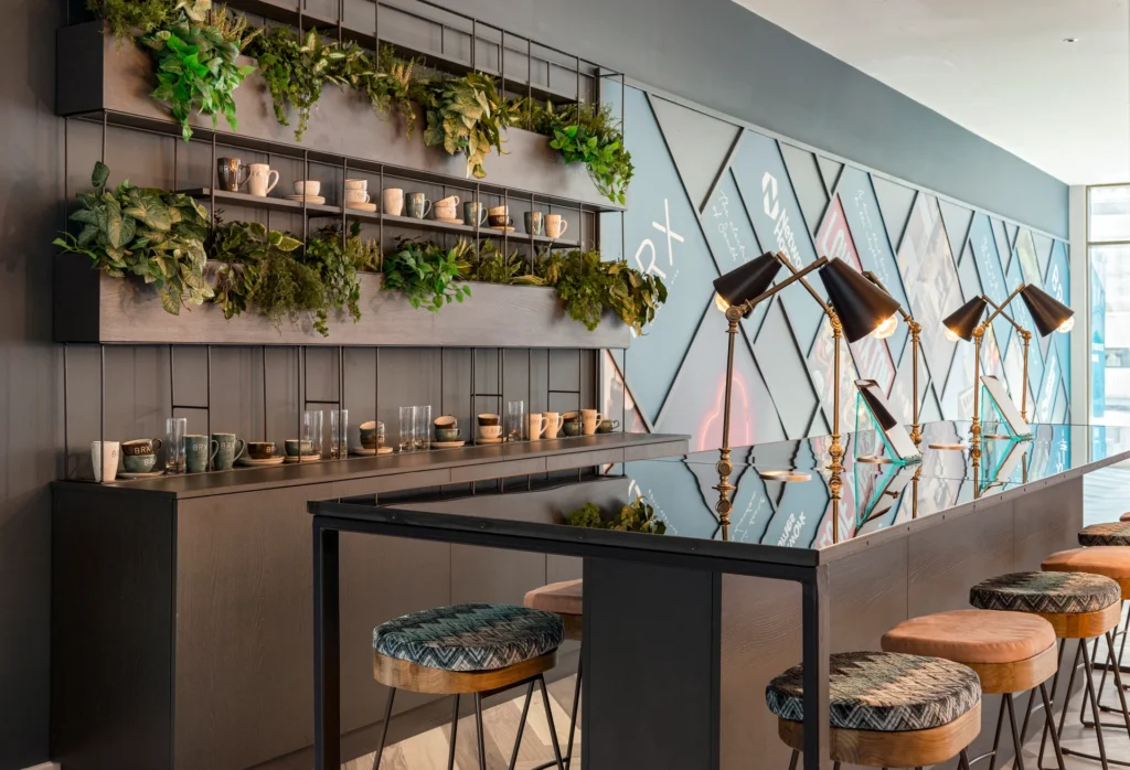 Modern bar area featuring a sleek countertop, decorative plants, and unique stools in a stylish interior setting.