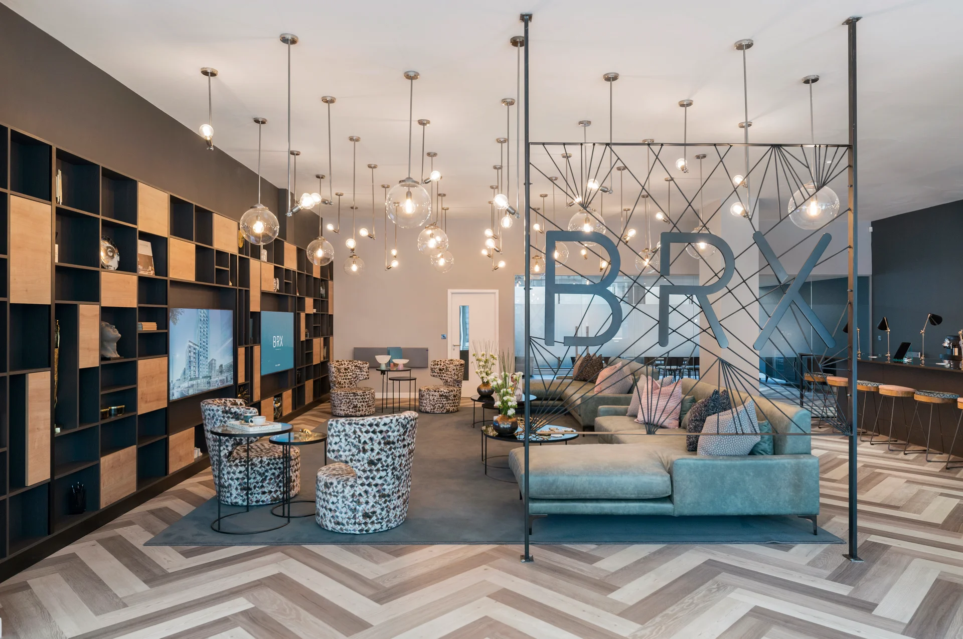 Modern lounge area with stylish furniture, decorative lighting, and an open shelving unit showcasing books and decor.