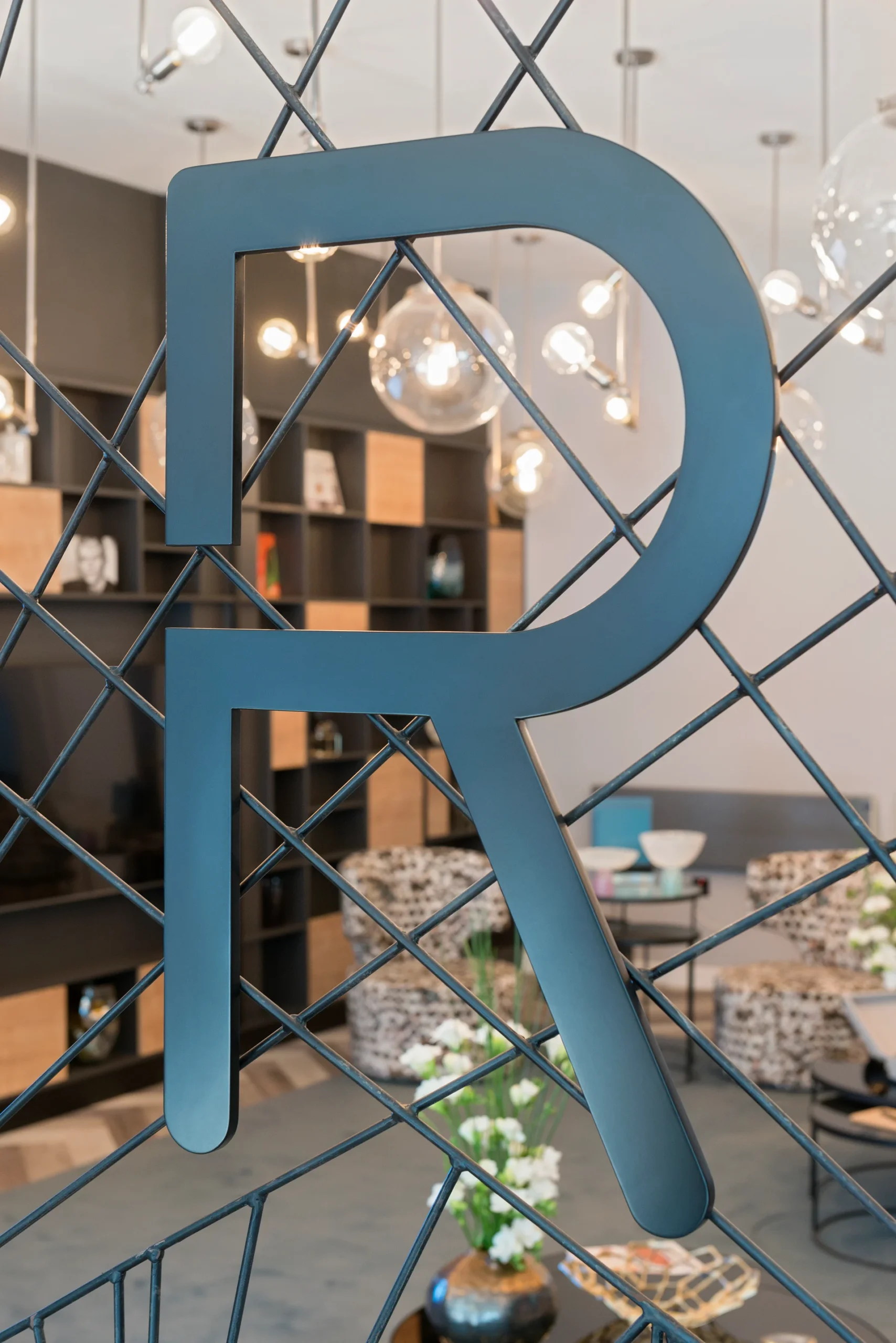 Stylized blue logo featuring the letters "R" and "P" on a decorative lattice background in a modern space.