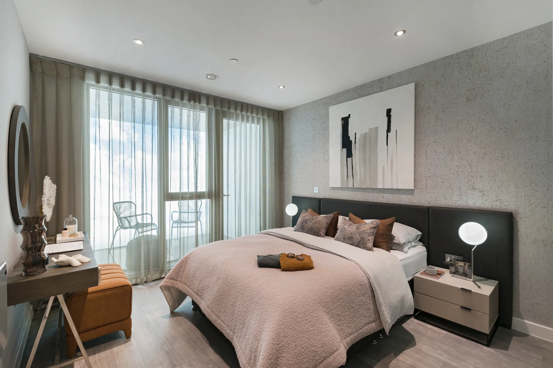Modern bedroom featuring a king-sized bed, abstract art, and large windows with sheer curtains.