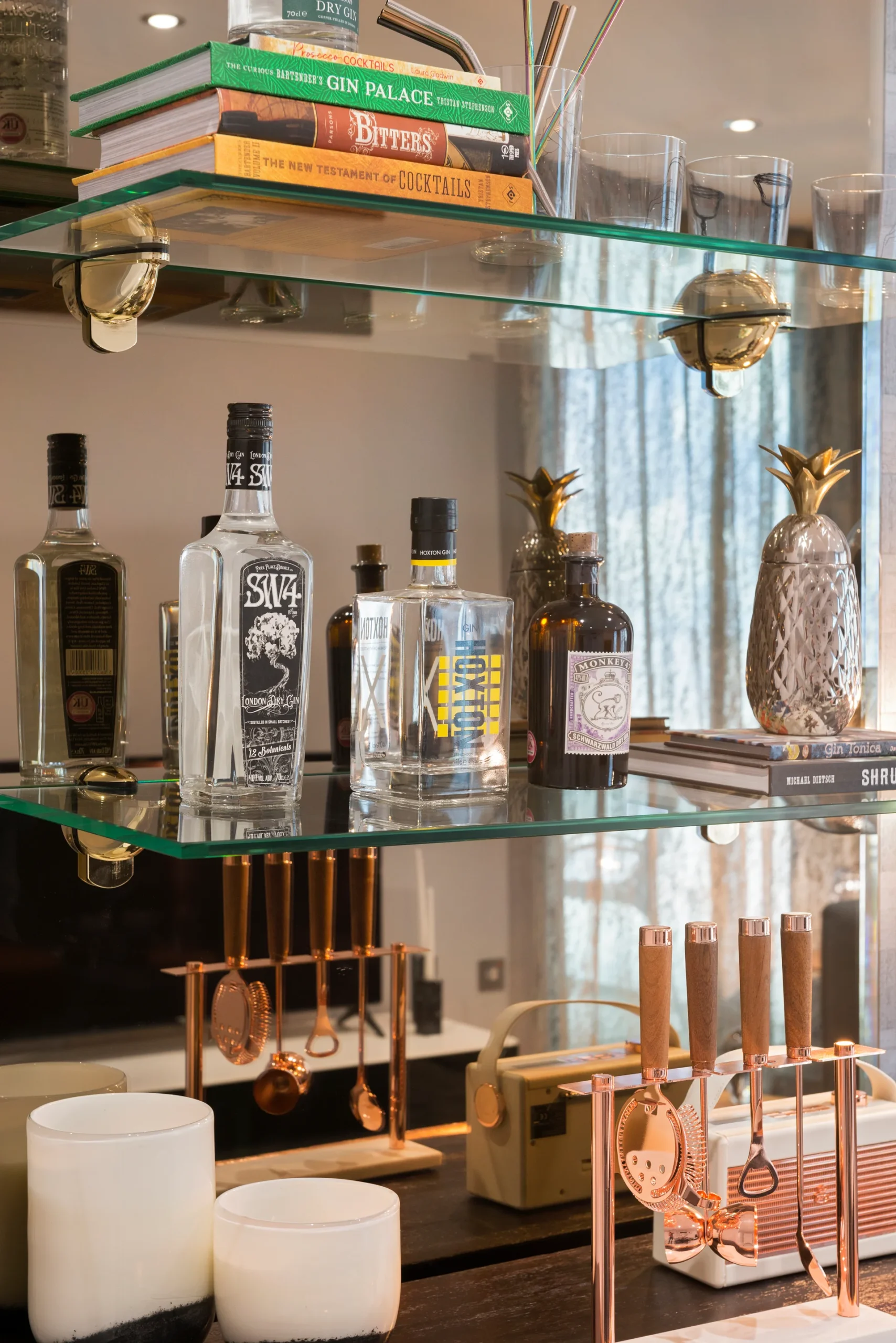 Glass shelves displaying various bottles, books, and decorative items in a modern interior setting.