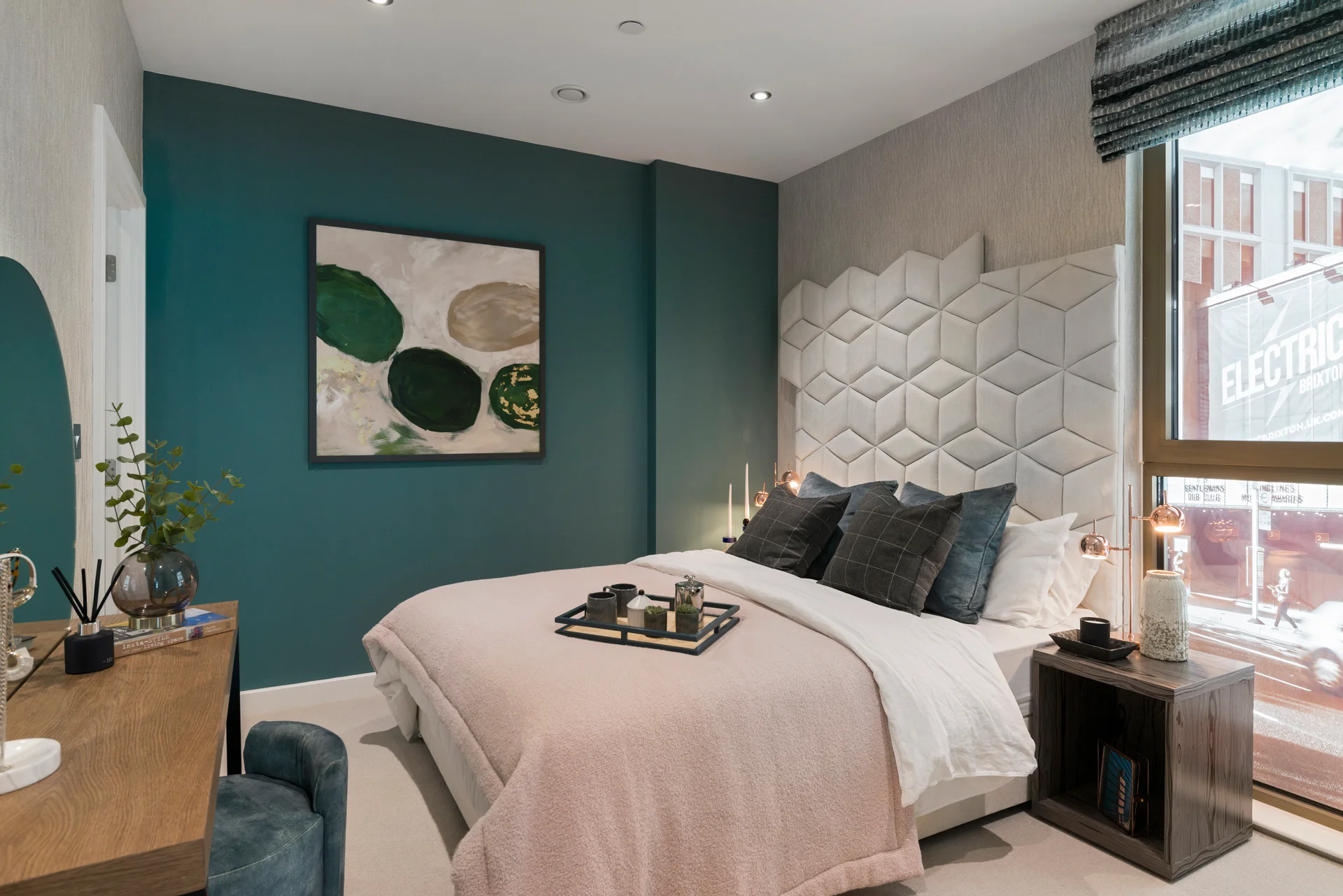 Modern bedroom with teal accent wall, textured headboard, and cozy decor, including artwork and bedside table.