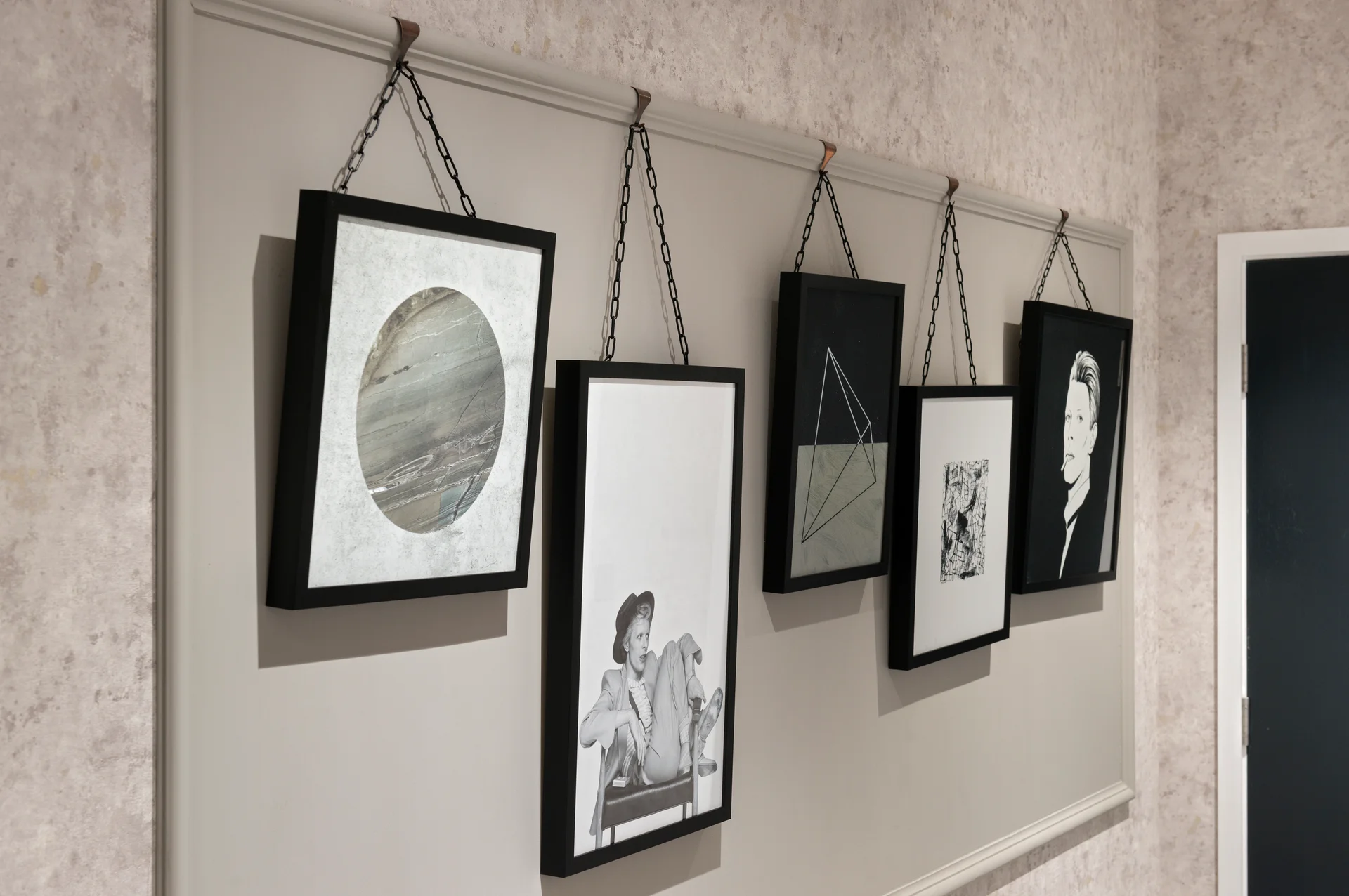 Six framed artworks hanging on a wall, featuring abstract designs and portraits, in a modern interior setting.
