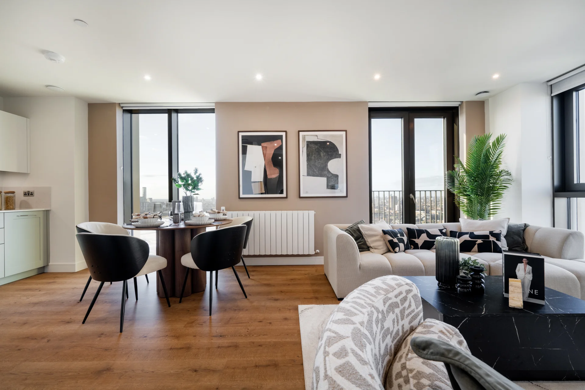 Stylish living space featuring a dining area, modern furnishings, artwork, and large windows with natural light.