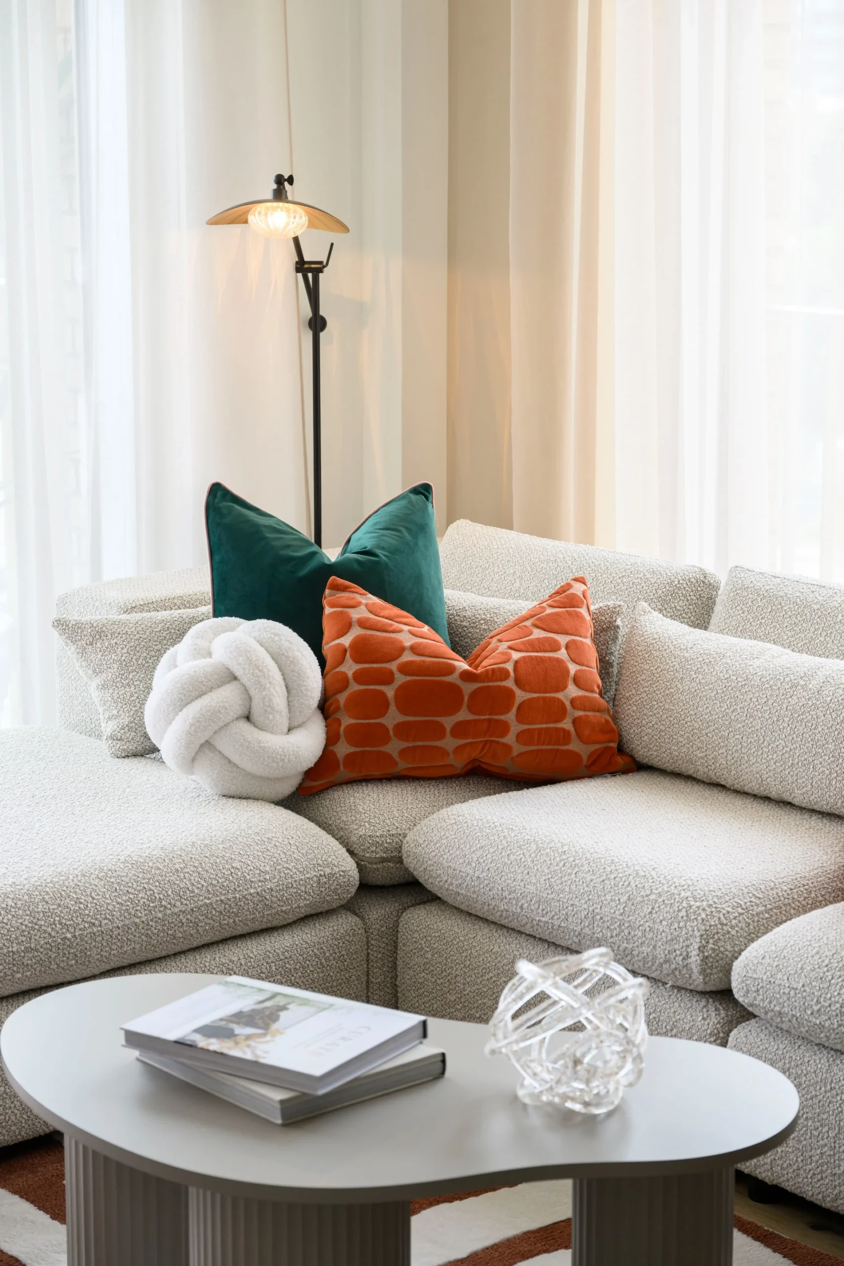 Cozy living room corner with a light-colored sofa, decorative pillows, a coffee table, and a lamp.